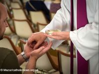 The hands of a priest anoint those of a sick person
