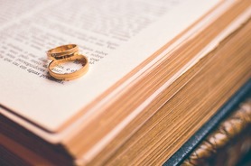 Two gold wedding rings on an open Bible