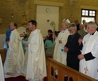 Bishop Kieron, wearing a hold mitre and carrying his crozier, and two priests process past the congregation at the beginning of the Consecration Mass